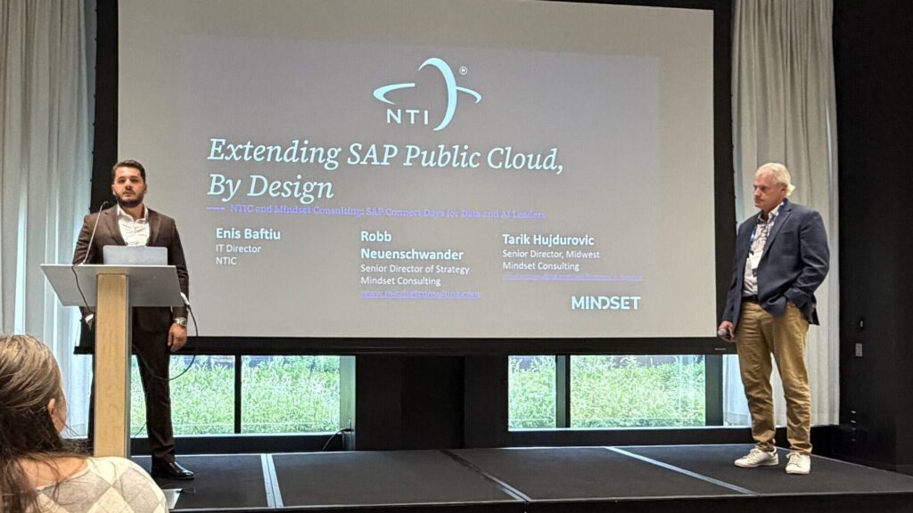 Enis Baftiu of NTIC at the podium and Robb Neuenschwander of Mindset on stage at SAP Connect Days Chicago, September 2026, under the title slide Extending SAP Public Cloud, By Design.